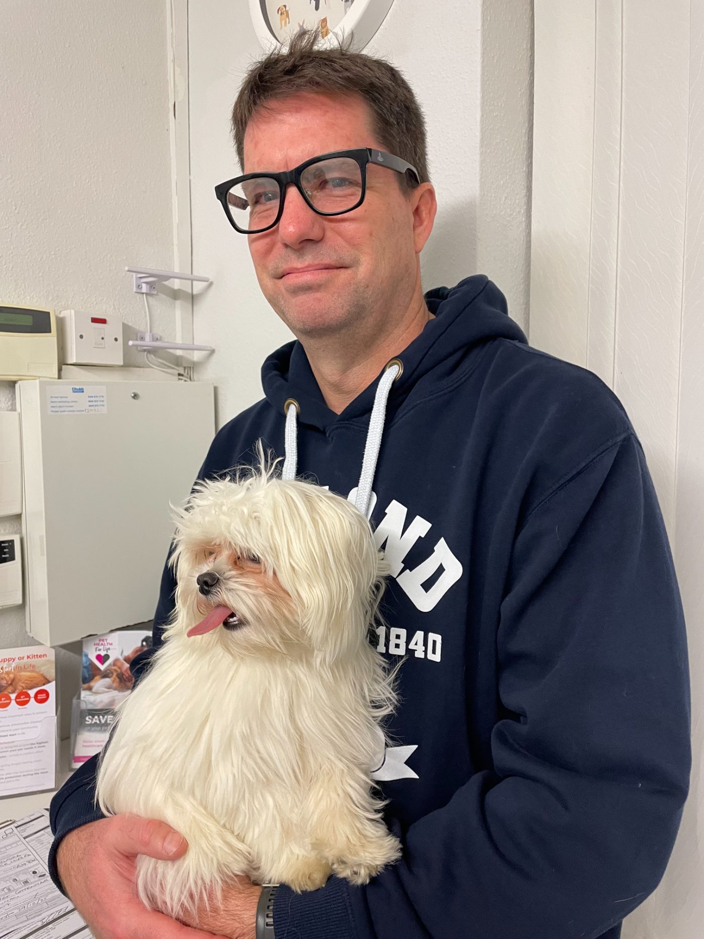 Stuart Maclachlan holding his small white dog, Pickle, black and white.